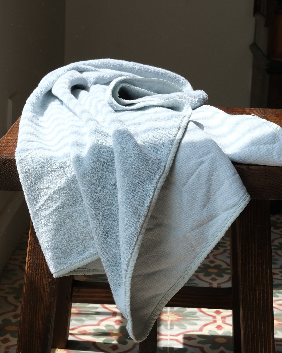 Siwa reversible Egyptian cotton towel on a wooden stool